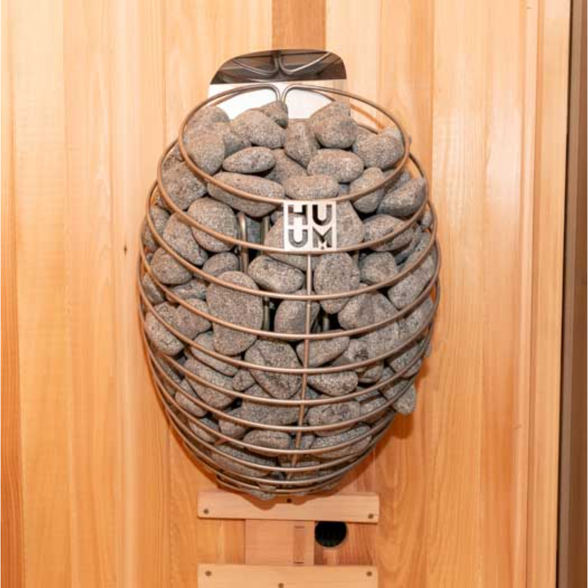 A wall-mounted electric sauna heater with a sleek, rounded design and stainless steel details, filled with sauna stones.