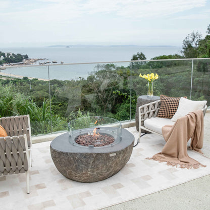 Outdoor patio with fire pit table and chairs overlooking a scenic view.
