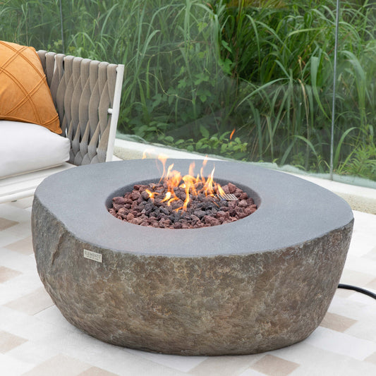Fire pit table with flames in a garden setting with chairs and cushions.