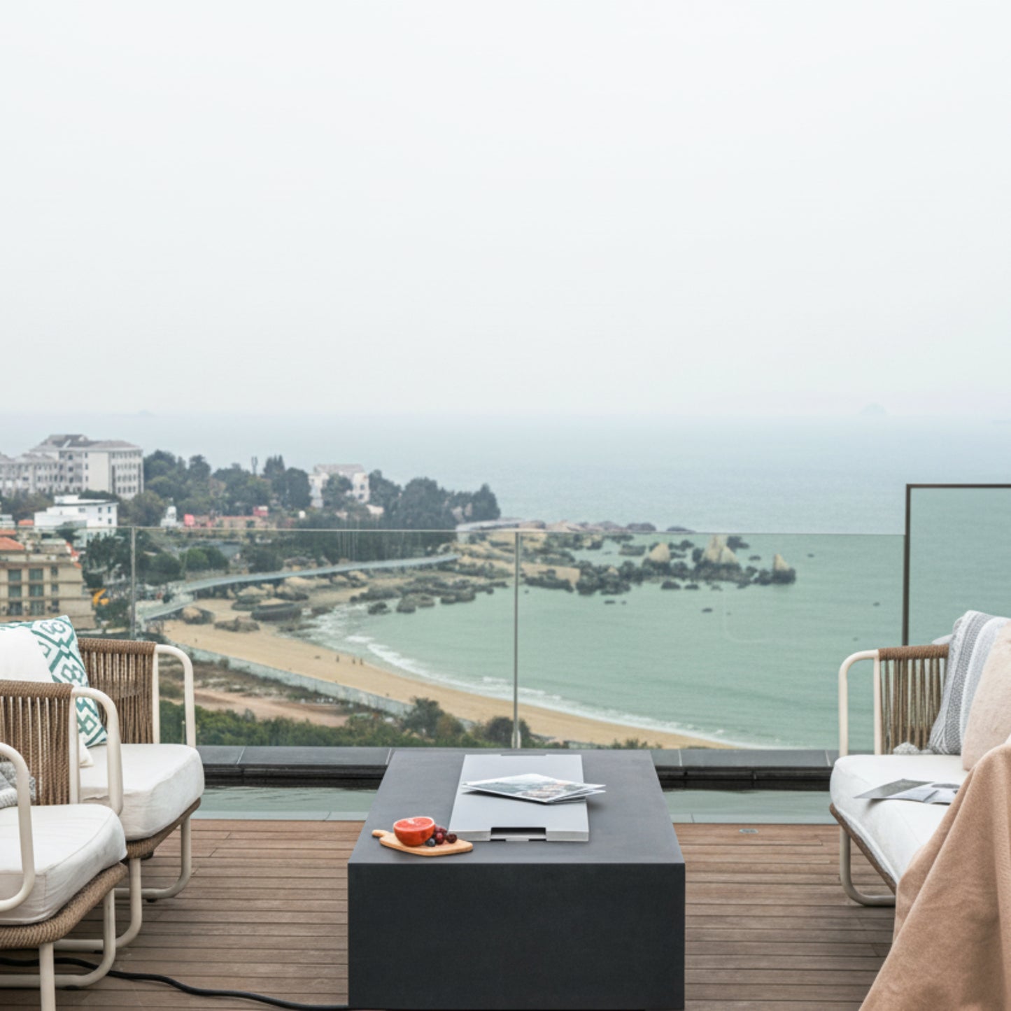 Outdoor patio with furniture and a scenic view of a beach and city.