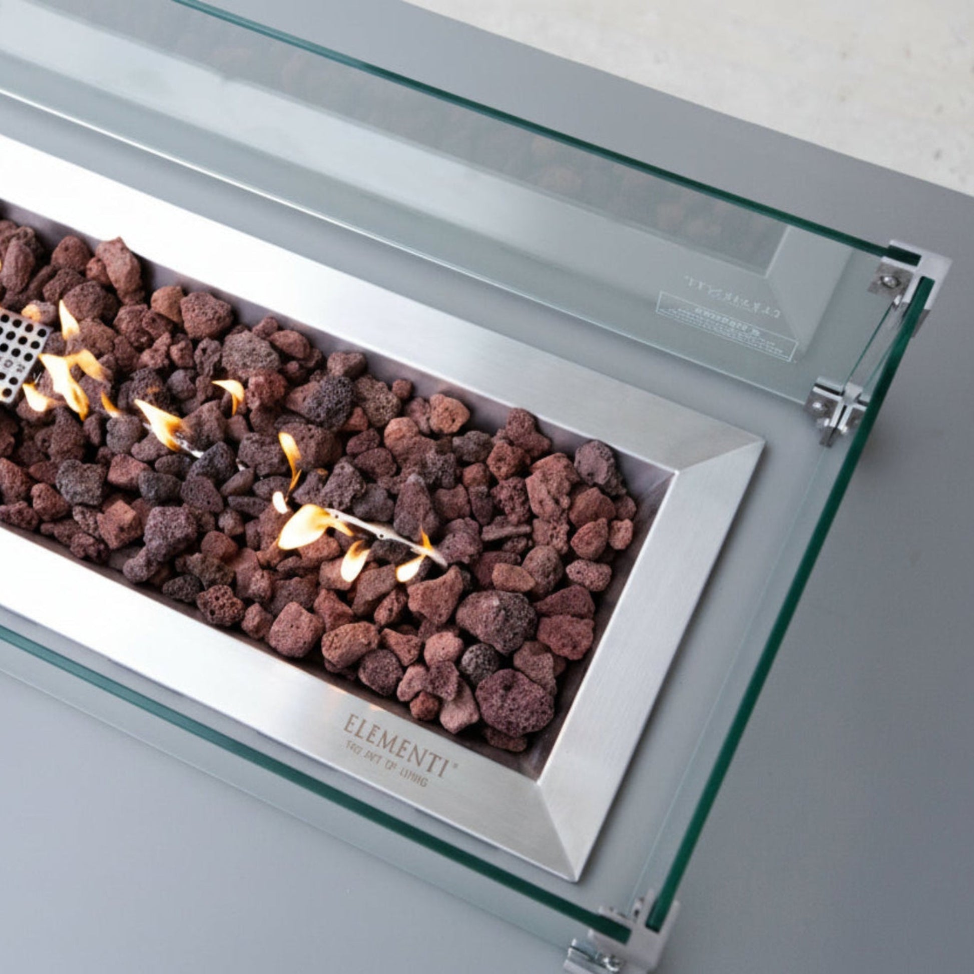 Modern gas fireplace with glass front and visible flames, featuring the Elementi brand.